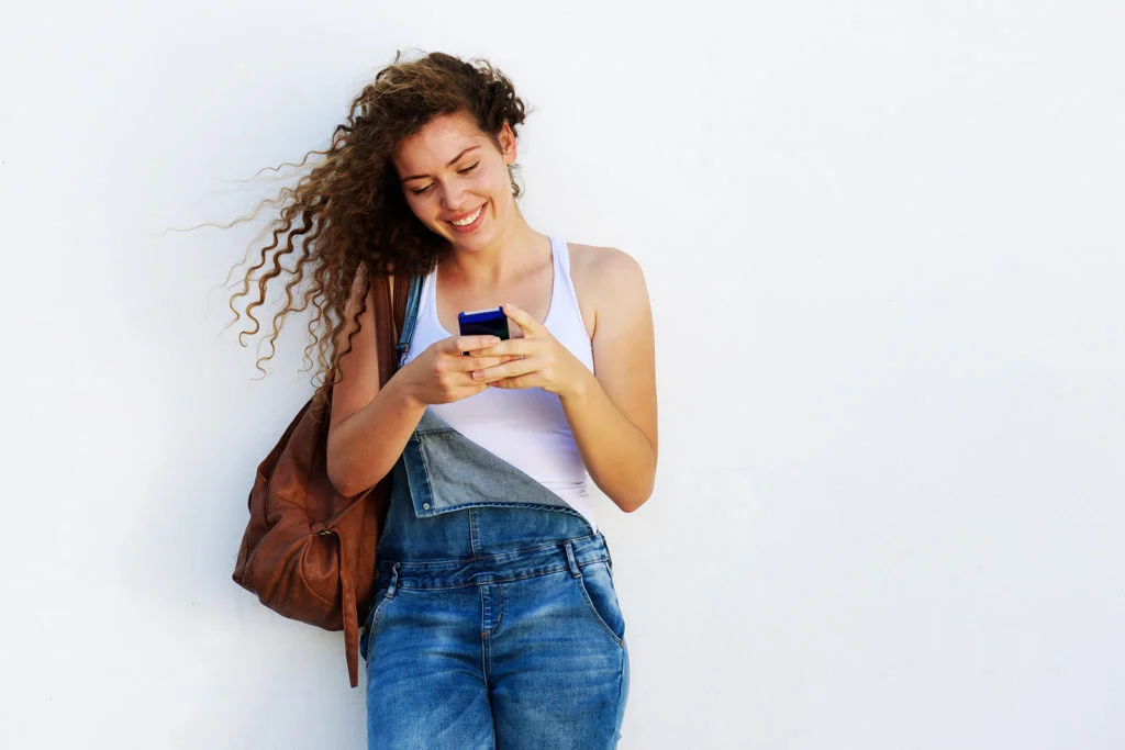 Menina feliz digitando no celular.