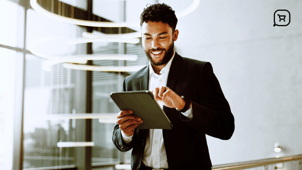 Um profissional sorridente, vestido de terno, utiliza um tablet em um ambiente corporativo moderno. A imagem transmite inovação e eficiência, reforçando o conceito de atendimento digital como uma solução ágil, inteligente e integrada para empresas que desejam melhorar a experiência do cliente.