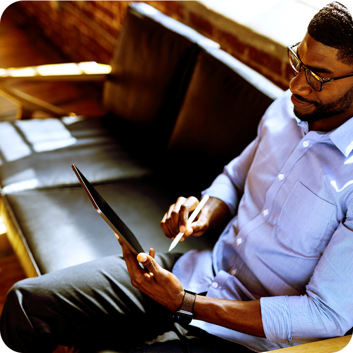 Alt: Profissional usando tablet e stylus em ambiente moderno de coworking.